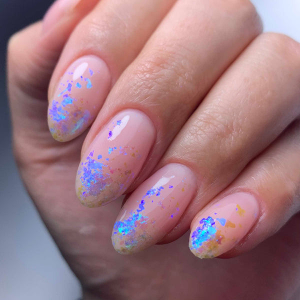 Blue nail art flakes over pink gel